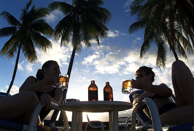 Foreign visitors to Fiji drink local beer at a beach-side hotel in Suva.