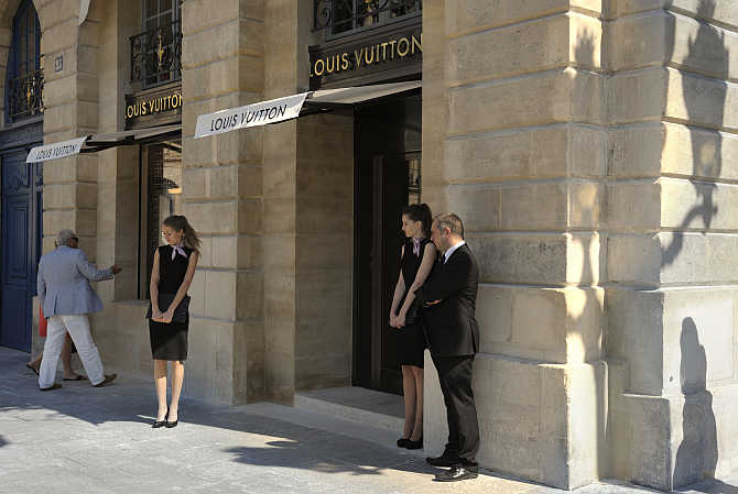 Hostesses stand in front of the entrance of LVMH's Louis Vuitton's jewellery store in Paris, France.