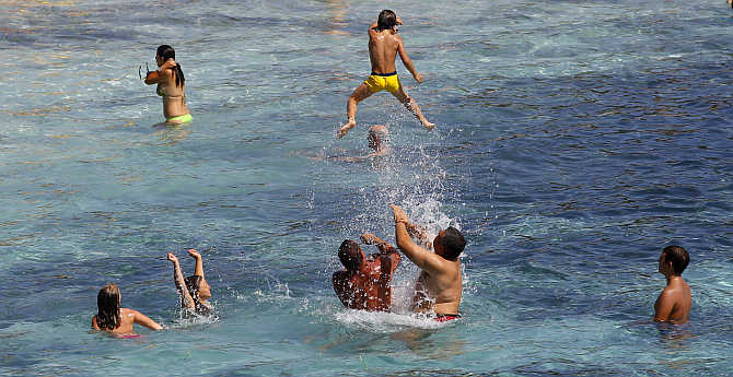 People play in the waters at the Ramizzo beach in the so-called 'Emerald Coast' off the Sardinia island in Italy.