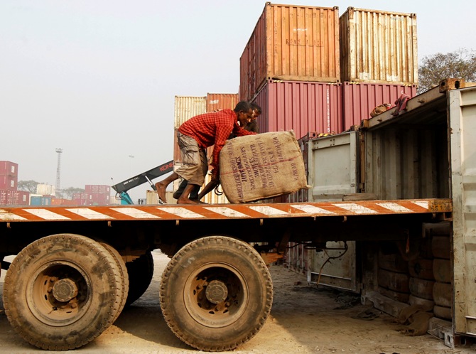 Labourers unload goods from a trailer at a port in Kolkata January 10, 2014.