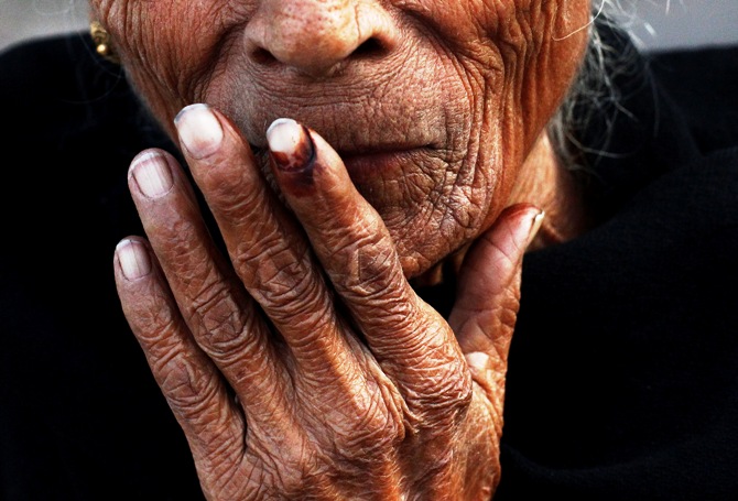 An elderly woman places her ink-marked finger on her lips after casting her vote outside a polling booth during the state assembly election in Delhi December 4, 2013. 