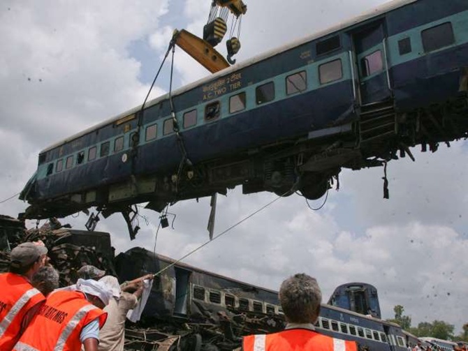 Rescue workers help to move a carriage, lifted by crane, from a passenger train which derailed near Fatehpur.