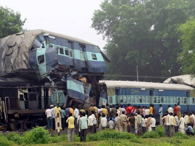 Onlookers stand beside the damaged carriages of a train at the site of an accident near Badarwas station.