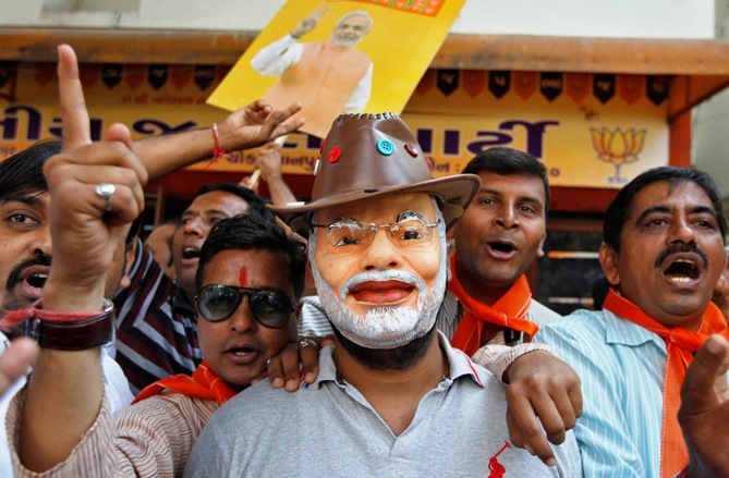 A supporter wearing a mask of Gujarat's Chief Minister Narendra Modi celebrates outside the party's headquarters in Ahmedabad December 8, 2013.