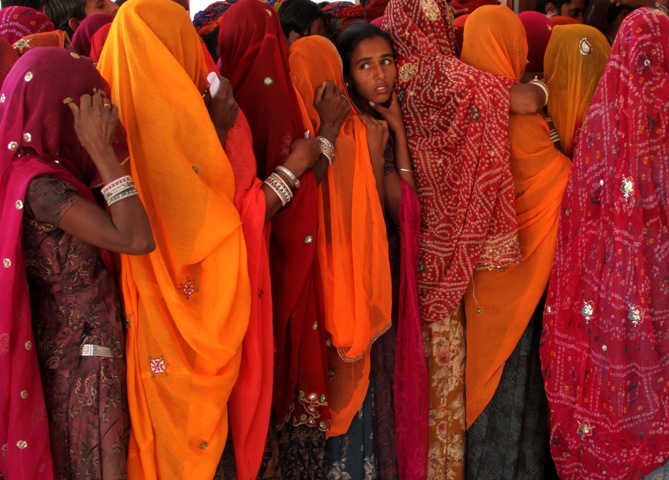 Women line up in a queue outside a polling booth to cast their vote during the state assembly election in Birchiwayas village in Ajmer district, Rajasthan, December 1, 2013.