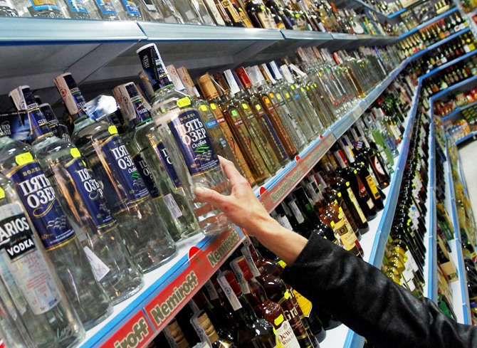 A customer takes a bottle of vodka from a shelf at a Russian supermarket in Benidorm.