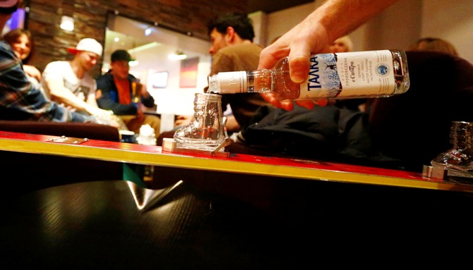 A man fills Vodka into a glass shaped into a miniature ski boot fixed in a customized binding at shot ski, in the bar of a hotel in the winter sport resort of Rosa Khutor, a venue for the Sochi 2014 Winter Olympics near Sochi.