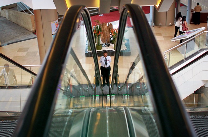 A private security personnel stands guard between escalators inside a shopping mall in Mumbai.