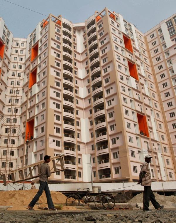 Labourers walk past a residential estate under construction in Kolkata.