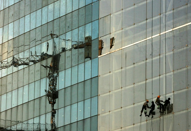 Workers clean windows on a building under construction in Hyderabad.