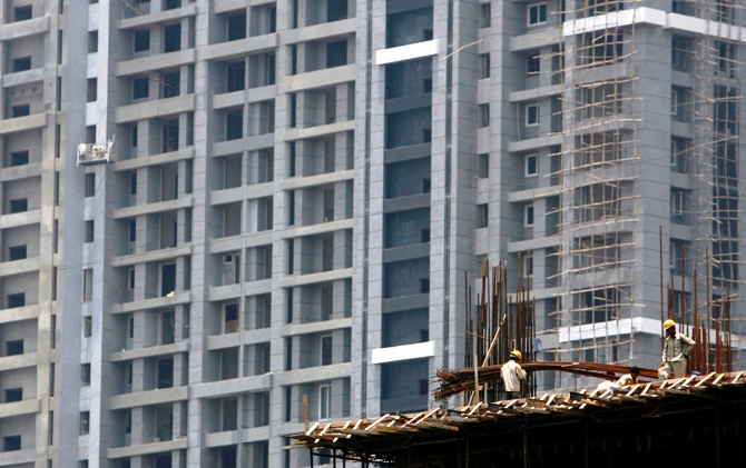 This file photograph shows workers standing on top of a building under construction in Mumbai. 