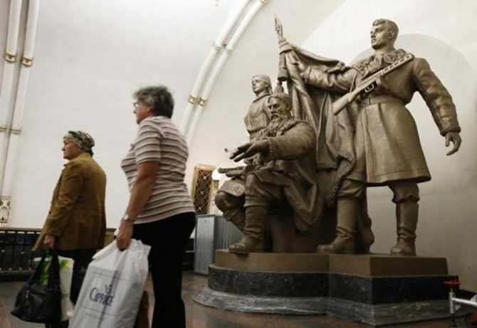Women walk past a statue in Belorusskaya metro station in Moscow.