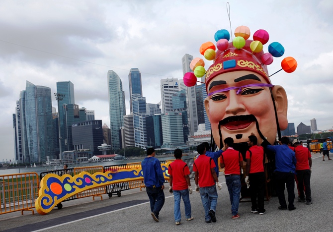 Workers assemble a God of Fortune statue as part of Chinese New Year decorations along the skyline of Singapore.