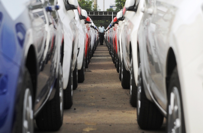 An employee walks between parked Hyundai cars ready for shipment at a port in Chennai.