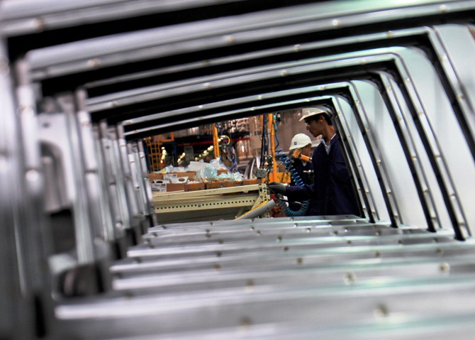 Employees are seen working through the doors of Chevrolet Beat cars on an assembly line at the General Motors plant in Talegaon.
