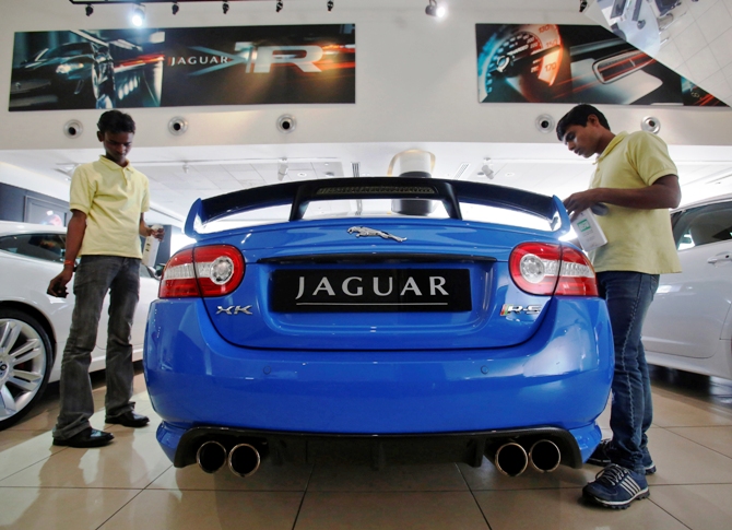 Showroom attendants polish a Jaguar vehicle at a Jaguar Land Rover showroom in Mumbai.