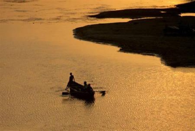 A man rows his boat in the waters of river Ganga during the sunset in Allahabad.