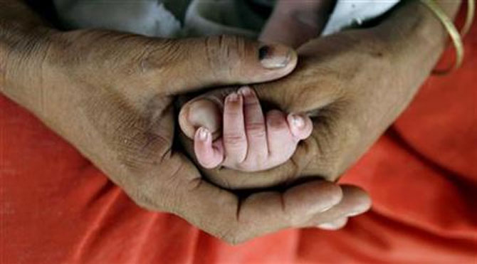 A mother holds the hand of her newly born child in Haryana.