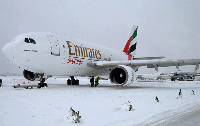 Airport officials walk under an Emirates A310 Airbus cargo plane in the snow at Ataturk Airport in Istanbul.