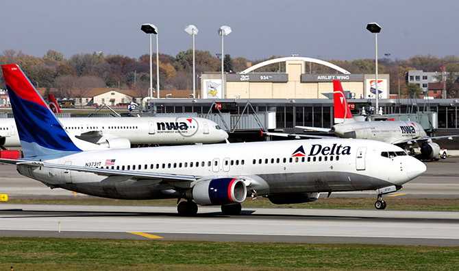 A Delta Air Lines jet takes off past a Northwest Airline jets parked at gates at the Minneapolis St.Paul International Airport in Minneapolis.