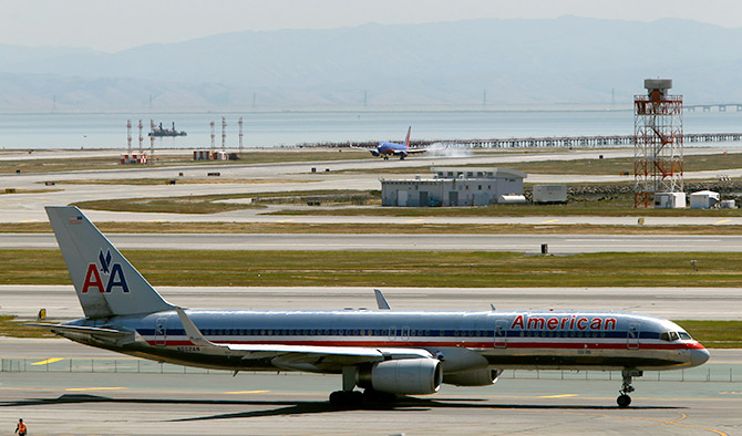 An American Airlines passenger jet taxis to a runway as a Southwest Airlines jet (rear) lands at San Francisco International Airport.