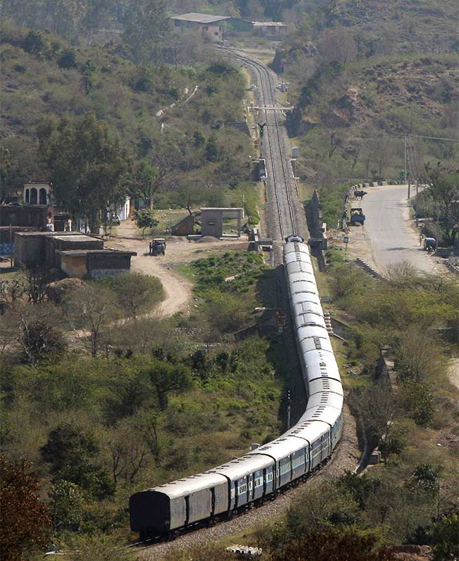 A passenger train moves along the Jammu-Udhampur rail line.