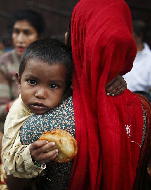 A woman carries a child as she begs for money.