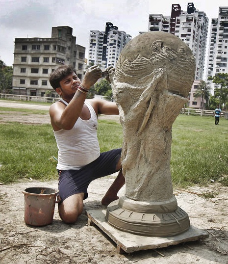 Sajal Mohanty, 27, an artisan, makes a four-feet high clay replica of a World Cup trophy outside a workshop in Kolkata.