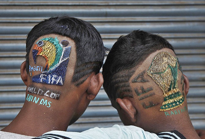 Soccer fans pose after getting fancy hairdos by Indian hair stylist Rabin Das outside his salon near Kolkata.