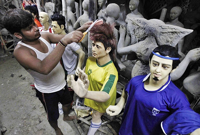 An artisan cuts the hair of a clay model depicting Brazilian soccer player Neymar at a workshop in Kolkata.