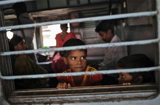 A girl looks out through the window of a passenger train at a railway station in New Delhi.