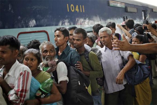 Passengers stand in a queue to board a train at a railway station in New Delhi.