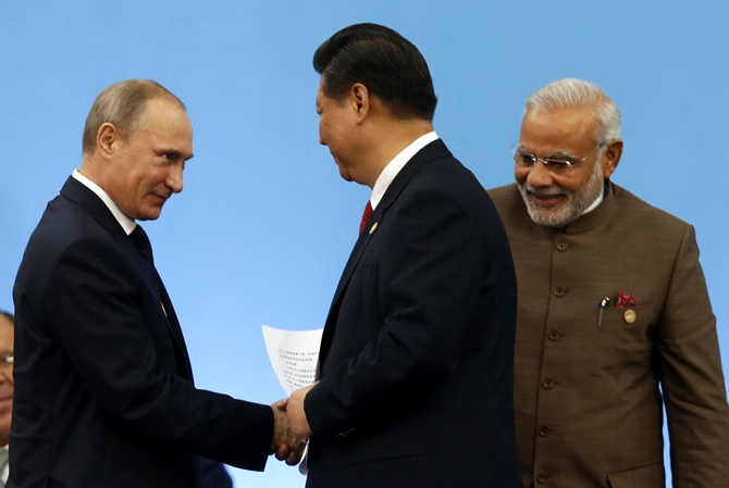 Russia's President Vladimir Putin (L) shakes hands with China's President Xi Jinping as India's Prime Minister Narendra Modi (R) looks on during the VI BRICS Summit in Fortaleza.