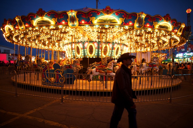 A cowboy walks by a carnival ride during day two of the Calgary Stampede in Calgar.