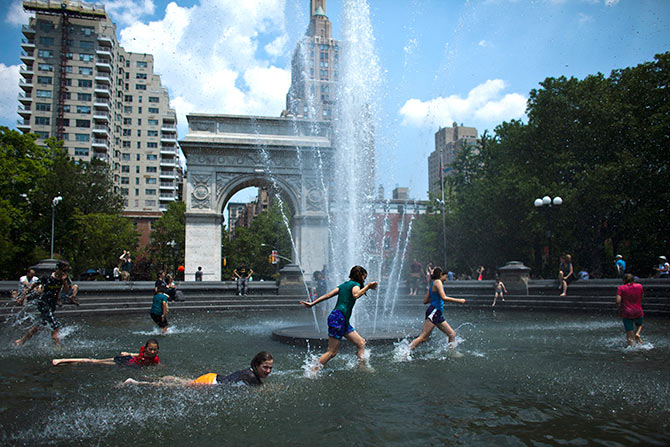 Kids enjoy the fountain at Washington Square during a warm day in New York.