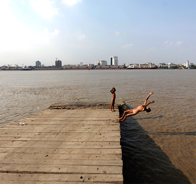 A boy dives into the water for a bath along the bank of the Yangon river.