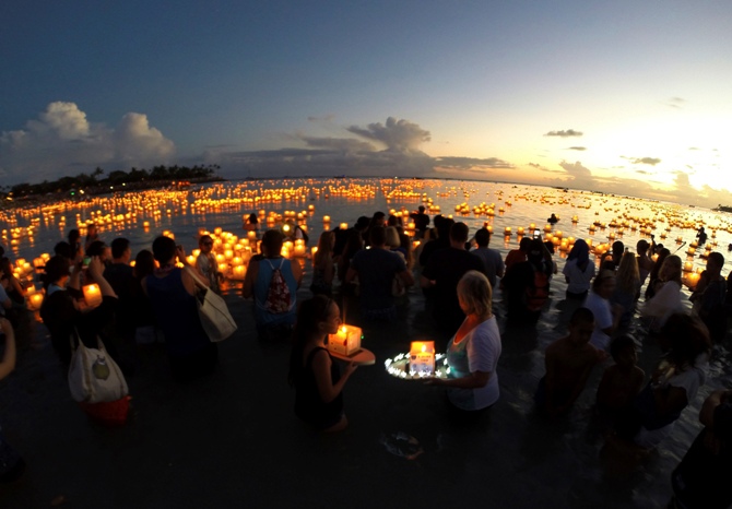 A large crowd gathers to release and watch floating lanterns on the water after being released during a ceremony marking remembrance and reflection, held by Shinnyo-en Buddhists honoring victims of war, famine, and natural disasters on Memorial Day, at Ala Moana Beach Park in Honolulu.