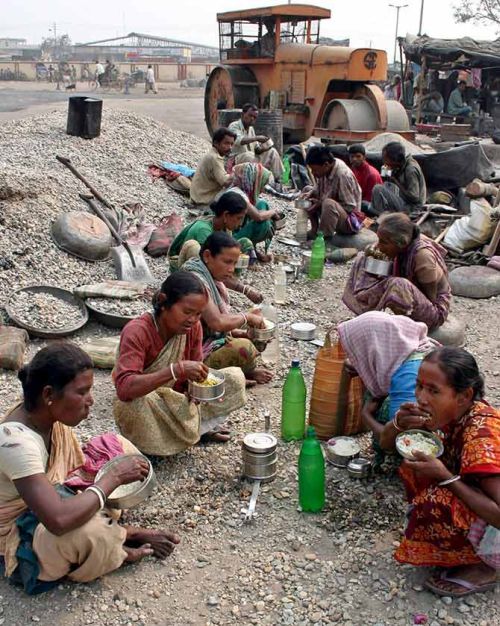 Road construction workers eat food during a break from work in Siliguri.