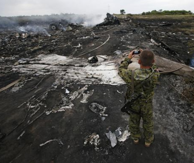 An armed pro-Russian separatist takes pictures at the site of a Malaysia Airlines Boeing 777 plane crash near the settlement of Grabovo in the Donetsk region.