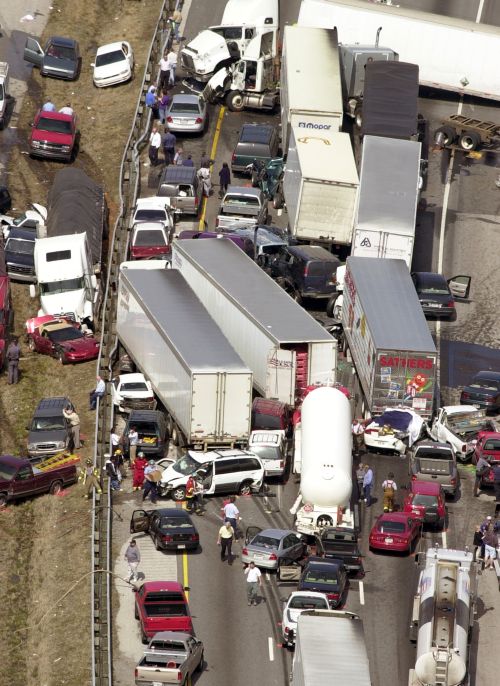 Dozens of vehicles sit on a highway after a deadly pileup along a foggy stretch of road.