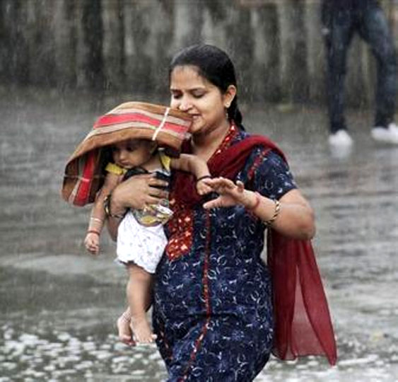 A woman carries her child through a heavy rain shower in Chandigarh.