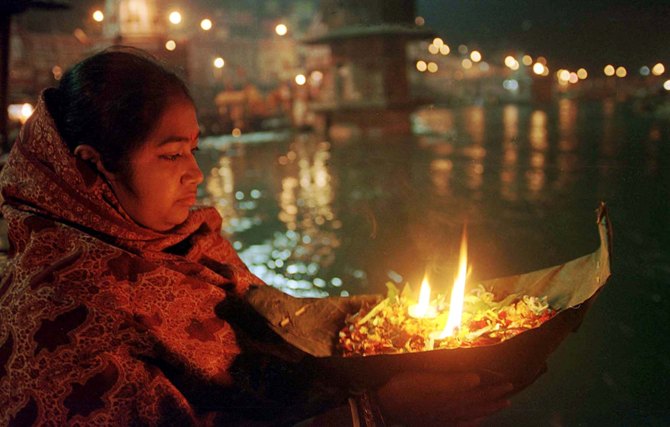 A woman prays with her offering to the Ganges river in Haridwar.