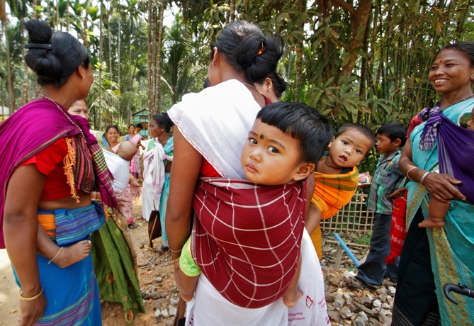 Women carrying their children stand after casting their vote at a polling station at Amguri village in Assam.
