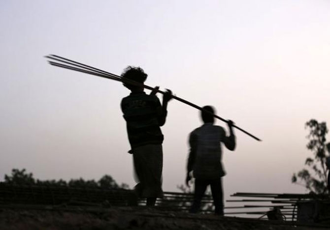 Labourers carry iron rods at the construction site of a flyover on the outskirts of Ahmedabad.