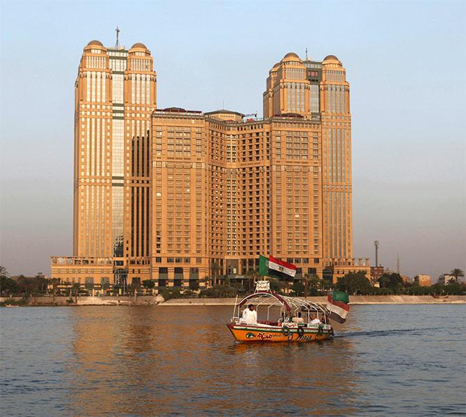 A small cruise boat passes Nile City Towers, which is owned by Naguib Sawiris the owner of Orascom Telecom, overlooking the river Nile in Cairo.