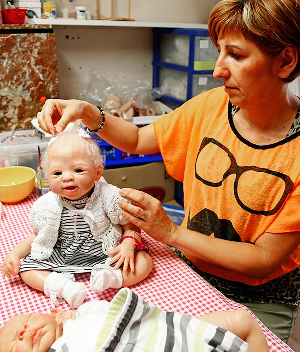 Belgian artist Beatrice Van Landeghem adjusts the hair of Sofia, one of her life-like 'Reborn Baby' dolls, at her workshop called 'La nurserie des Tis Lous De Bea' in La Louviere, southern Belgium.