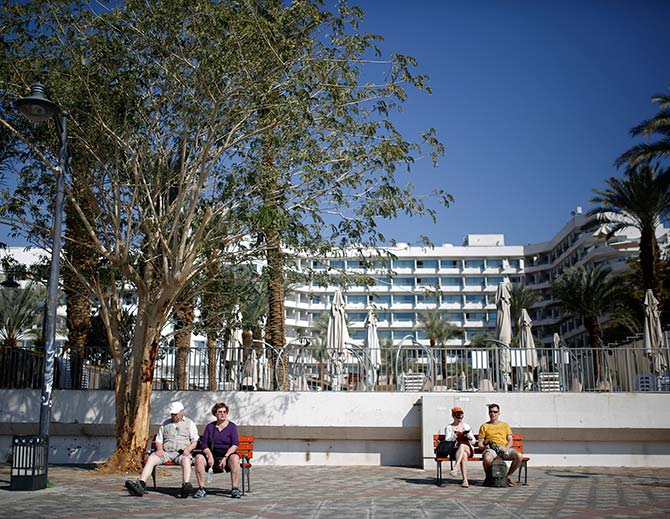 People rest on benches outside a hotel in the Red Sea resort city of Eilat, one of Israel's most popular holiday spots.