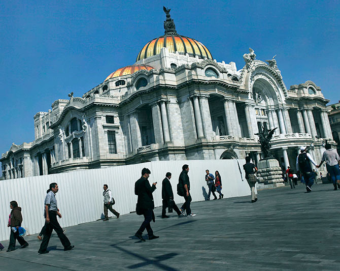 People walk in front of the Palace of Fine Arts in Mexico City.