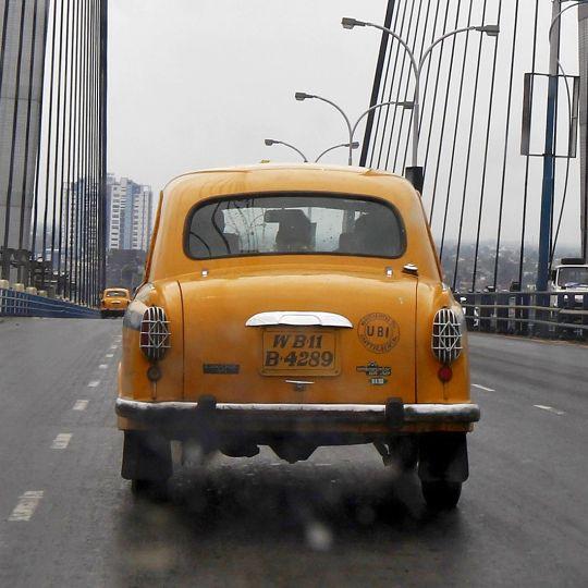 A yellow ambassador taxi crosses the Vidyasagar Setu bridge in Kolkata.