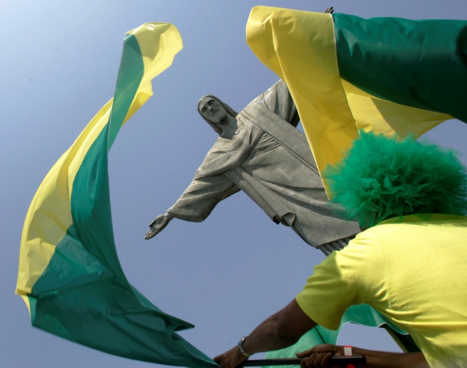 This file photograph shows a fan waving a flag in front of the Christ the Redeemer statue in Rio de Janeiro.